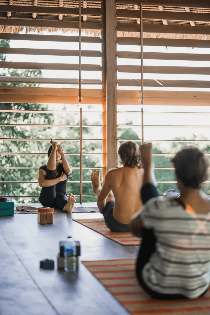 Yoga students spread across the yoga Shala at Ashtari with the yoga instructor in focus, surrounded by beautiful tropical green nature