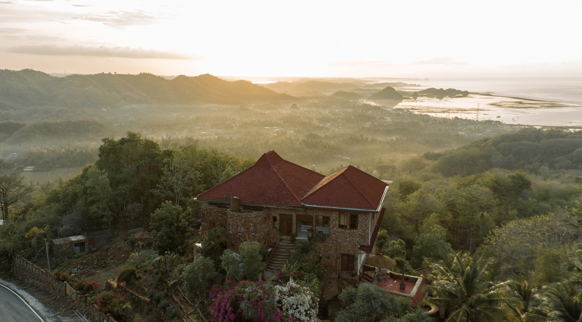 Drone view of ashtari location, yoga shala, restaurant, stone room, loft with a sunrise background of the entire city of Kuta Lombok