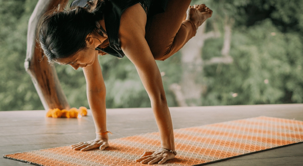 Almitra performing a Vinyasa Ashtanga pose surrounded by green nature at Ashtari in Kuta Lombok