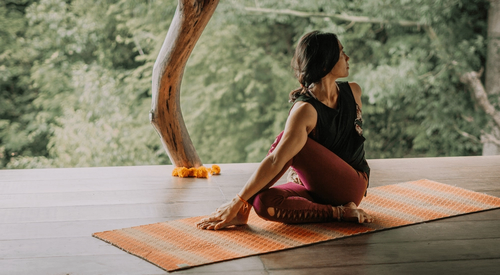 Almitra performing a yin yoga meditation pose surrounded y green nature at Ashtari in Kuta Lombok